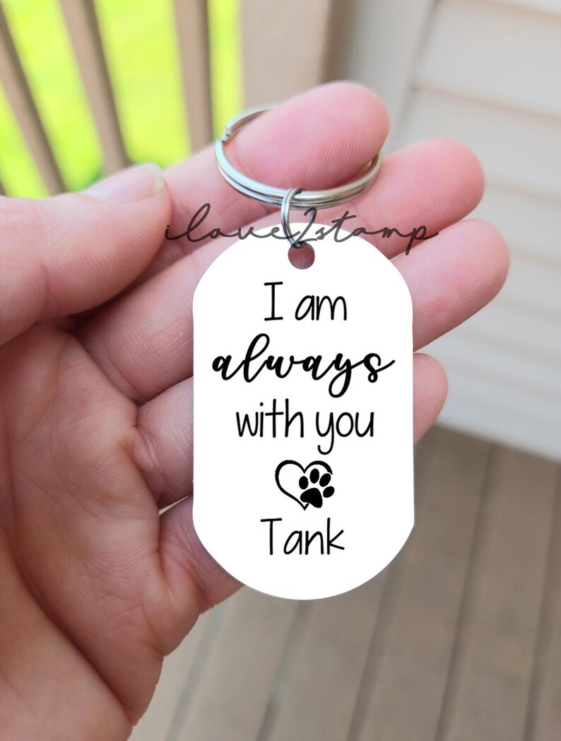 May include: White oval keychain with the text "I am always with you" and a paw print inside a heart. The name "Tank" is printed below the heart.
