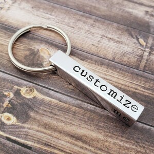 May include: Silver keychain with a rectangular bar that says "customize me".