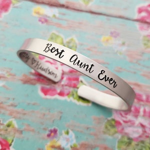 May include: Silver bracelet with the inscription "Best Aunt Ever" engraved on it.
