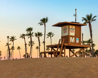 May include: A brown lifeguard tower stands on a sandy beach, surrounded by palm trees under a gradient sky of orange and blue. The tower has a ladder, bench, and signs that read "NO LIFEGUARD ON DUTY KEEP OFF".