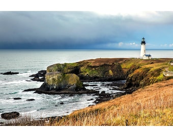 May include: A coastal landscape featuring a white lighthouse with a black top, situated on a grassy cliff. The scene includes rocky shores, ocean waves, and a cloudy sky. The lighthouse is a prominent feature in this scenic view.
