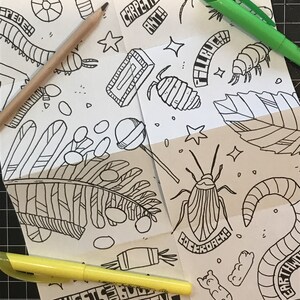 以下が含まれることがあります： 「SWEETS & BUGS COLORING ZINE」というタイトルの白黒の塗り絵。この本には、ゴキブリ、大工アリ、ダンゴムシなど、さまざまな虫のイラストが描かれています。イラストは星やその他の装飾的な要素で囲まれています。
