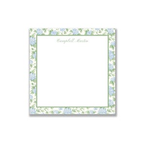 May include: Square notepad with a floral border featuring light blue hydrangea blooms and green leaves on a cream background. The text "Campbell Martin" is printed in the center.