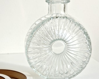 May include: A clear glass vase with a round, textured design. The vase has a wide opening and a small base.