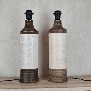 Op de afbeelding: Twee keramische tafellampen met bruine en witte gespikkelde bases en zwarte lampenkappen.