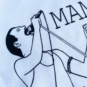 May include: Black and white line drawing of a person singing into a microphone with the word "MAM" in the background.