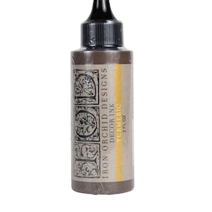 May include: A 2 fl oz bottle of Iron Orchid Designs Decor Ink in the color Turmeric. The bottle is brown with a black cap and a label with the brand name and color name.