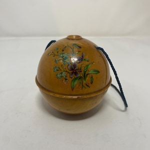 Puede incluir: Adorno redondo de madera con diseño floral en tonos azules, morados y verdes. Cuenta con una cuerda azul oscuro para colgar. La superficie de madera es de color marrón claro. Aproximadamente 7 cm de diámetro.
