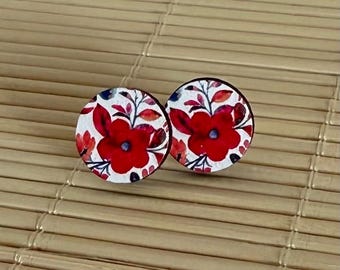 May include: A pair of round wooden earrings with a white background and a red floral pattern.