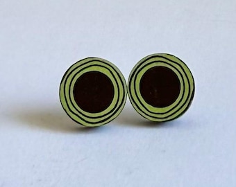 Könnte beinhalten: Ein Paar runde Ohrringe mit einem Design aus konzentrischen schwarzen und grünen Kreisen.