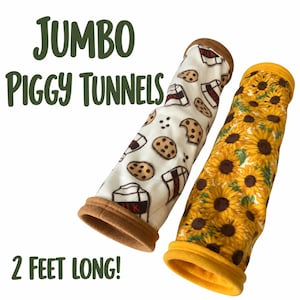 May include: Two cylindrical pet tunnels, 2 feet long, labeled JUMBO PIGGY TUNNELS. One tunnel is white with a brown milk carton and chocolate chip cookie pattern and tan ends. The other is yellow with a sunflower print and bright yellow ends.