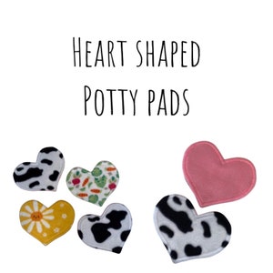 May include: Heart-shaped potty pads in various patterns, including cow print, floral, and a solid pink. The pads are arranged on a white background. Text at the top reads "HEART SHAPED POTTY PADS."