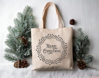 May include: A beige canvas tote bag with a black wreath design and the text "Merry Christmas" inside the wreath.