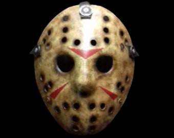 Op de afbeelding: Een wit hockeymasker met rode strepen en een zwarte band. Het masker heeft veel kleine gaatjes.