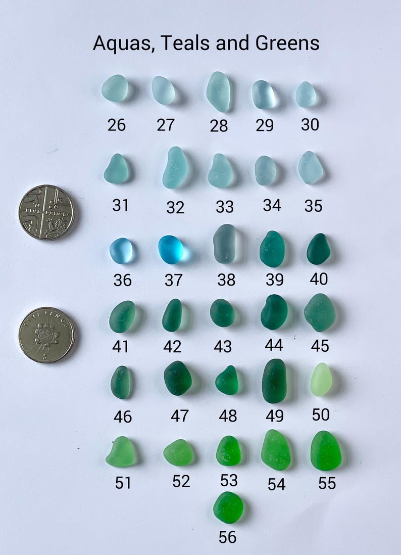 Puede incluir: Una variedad de vidrios marinos en tonos aguamarina, turquesa y verdes, numerados del 26 al 56. Dos monedas se colocan junto al vidrio marino para comparar el tama&ntilde;o. El texto "Aquas, Teals and Greens" est&aacute; en la parte superior.
