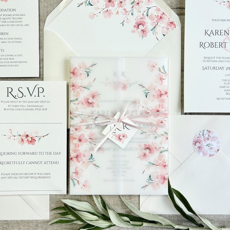 Pink cherry blossom wedding invitation with vellum jacket and sealed with ribbon and tag