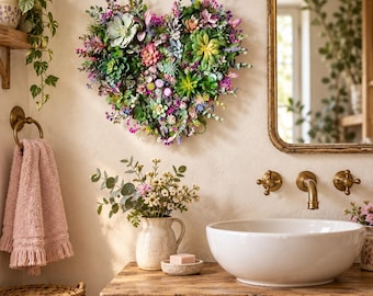 May include: A heart-shaped wall decoration composed of various artificial succulents and small purple, pink, and green flowers. The arrangement features a dense mix of textures and colours, including light green rosettes and vibrant floral accents.