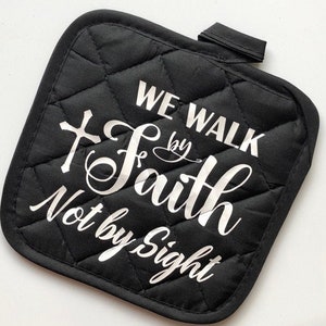 May include: Black quilted pot holder with a white cross and the text "We Walk by Faith Not by Sight".