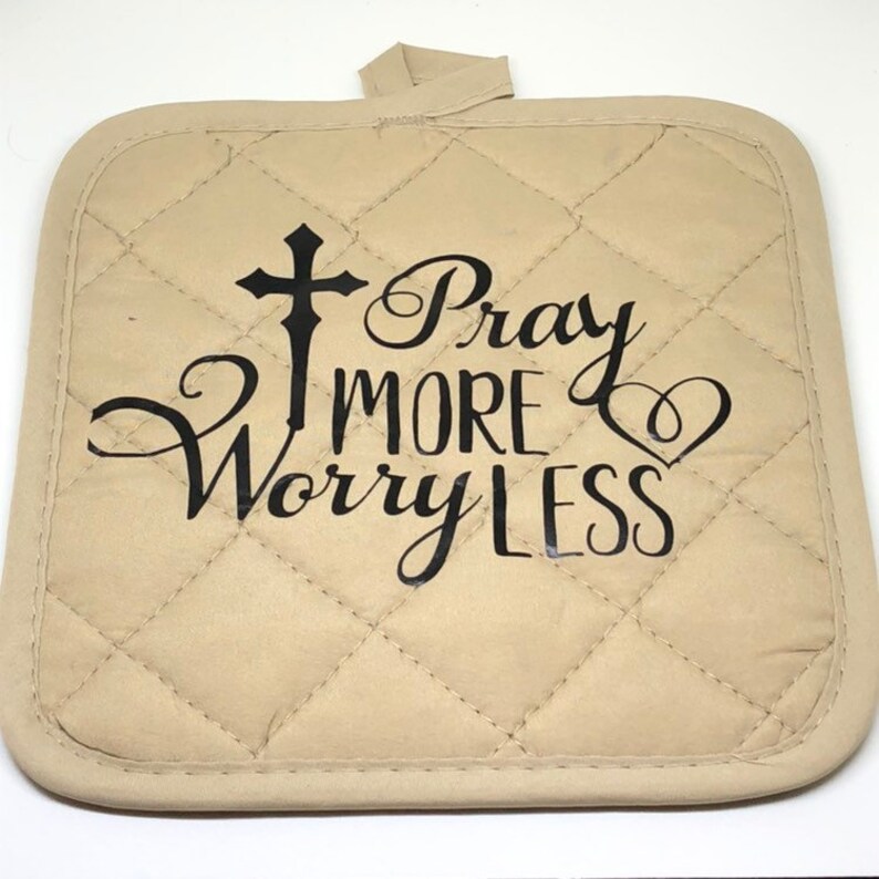 May include: Beige quilted hot pad with a black cross, heart, and the text "Pray More Worry Less".