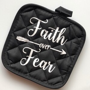 May include: Black quilted pot holder with a white arrow and the text "Faith over Fear" in a cursive font.