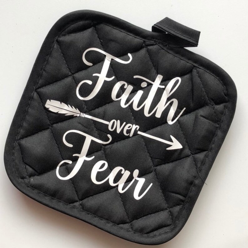 May include: Black quilted pot holder with a white arrow and the text "Faith over Fear" in a cursive font.