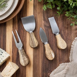 May include: A four-piece cheese knife set featuring stainless steel blades and light brown wooden handles. The set includes a two-pronged cheese fork, a wide flat cheese spade, a pointed cheese knife, and a rectangular cheese slicer blade.