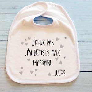 May include: White baby bib with the text "J'PEUX PAS J'AI B&Ecirc;TISES AVEC MARRAINE JULES" in black with gray hearts and stars.