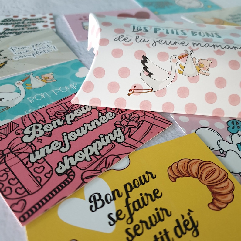 May include: A set of colorful gift tags with French text. The tags feature illustrations of a stork, a shopping bag, and a croissant. The text on the tags reads "Bon pour une nuit complete!" (Good for a complete night), "Bon pour une journee shopping" (Good for a day of shopping), and "Bon pour se faire servir tit dej" (Good for getting served breakfast).