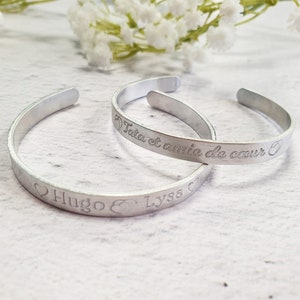 Op de afbeelding: Twee zilveren armbanden met gegraveerde berichten. De ene armband heeft de tekst "Tatia et amie de coeur" en de andere "Hugo & Lysa".