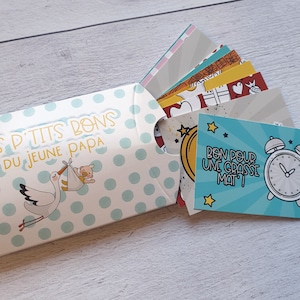 May include: A blue and white envelope with white polka dots and a stork carrying a baby. The envelope contains small cards with various illustrations and the text "Bon pour une grasse mat!"