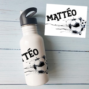 Könnte beinhalten: Weiße Wasserflasche mit schwarzem Deckel und einem schwarz-weißen Fußball-Motiv. Die Flasche trägt den Namen "MATTÉO".