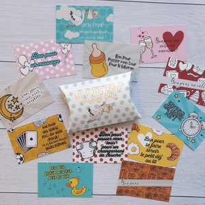 May include: A set of colorful cards with French text, each card depicting a different activity or task. The cards are arranged on a light wood surface. The text on the cards includes "Bon pour un massage", "Bon pour une nuit compl&egrave;te", "Bon pour passer mon tour pour le biberon", "Bon pour passer mon tour pour le bain", "Bon pour se faire servir le petit d&eacute;j au lit", "Bon pour un calin", "Bon pour une soir&eacute;e en amoureux", "Bon pour un gros mot", "Bon pour une soir&eacute;e on fait un autre b&eacute;b&eacute;!" and "Les p'tits bons du jeune papa".