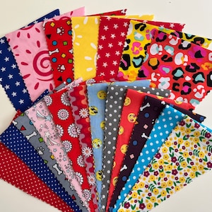 May include: A selection of patterned fabric squares in a variety of colours. Designs include stars, polka dots, and floral prints. The fabrics are in shades of red, blue, yellow, and pink, with a decorative, scalloped edge.