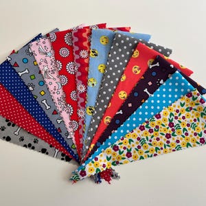 May include: A collection of 15 colourful fabric scraps with various patterns, including polka dots, stars, and emojis. The fabric scraps are arranged in a fan shape.