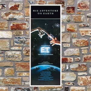 May include: A vertical movie poster for E.T. The Extra-Terrestrial featuring the iconic scene of two fingers touching against a starry space background, with the text HIS ADVENTURE ON EARTH, E.T. THE EXTRA-TERRESTRIAL, and additional film credits.