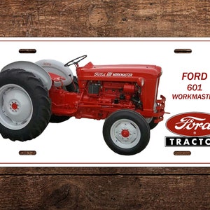 May include: A white metal sign with a red Ford 601 Workmaster tractor. The tractor has a white front wheel and a red engine. The sign also has the text "FORD 601 WORKMASTER" and a red Ford tractor logo.
