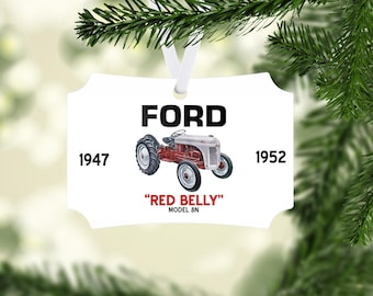 May include: White rectangular ornament with a vintage Ford tractor illustration. The ornament features the word "FORD" in bold black letters, the years 1947 and 1952, and the text "RED BELLY" MODEL 8N. A white ribbon is attached for hanging.
