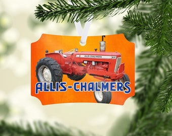 Puede incluir: Adorno navideño rectangular con un tractor Allis-Chalmers D17 rojo sobre un fondo naranja. El tractor tiene neumáticos negros grandes y llantas blancas. Las palabras "ALLIS-CHALMERS" están en azul y blanco.