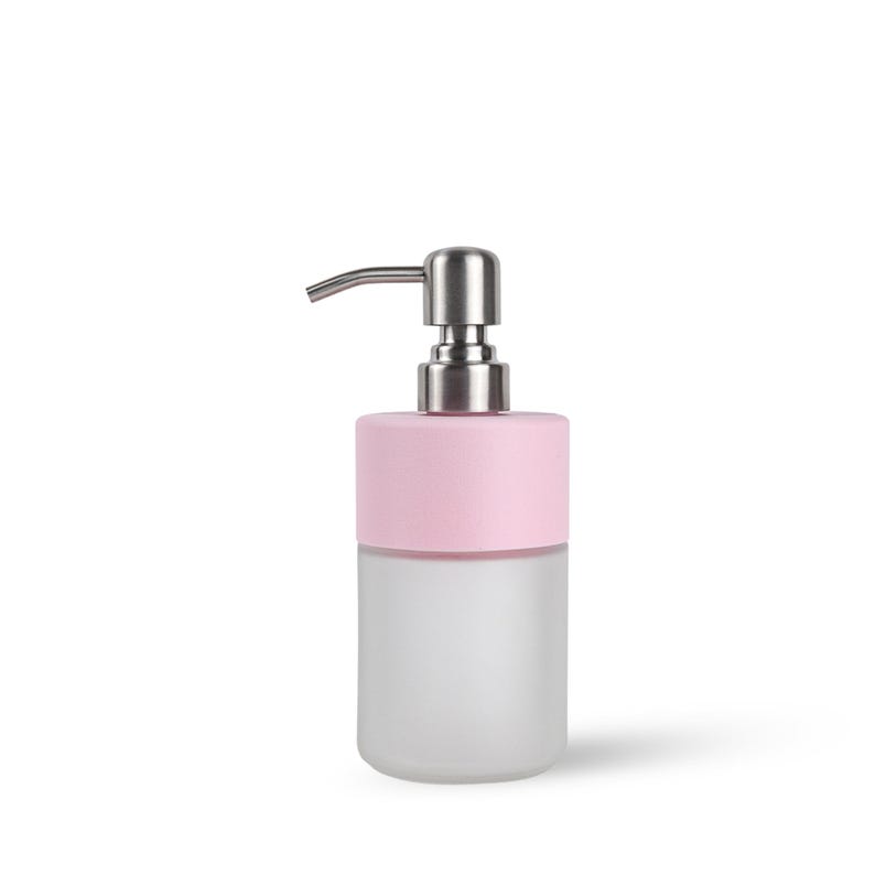 Op de afbeelding: Een moderne zeepdispenser met een basis van matglas en een lichtroze bovenkant. De dispenser heeft een zilveren pomp en tuit. Het ontwerp is minimalistisch en geschikt voor een badkamer of keuken.