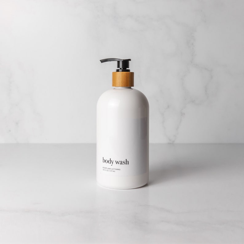 Minimalist style refillable white plastic conditioner bottle with black bamboo pump on an organized decluttered marble bathroom counter. Holds 16 fluid ounces/500 milliliters and comes in a set of 4 with shampoo, conditioner, and body wash.