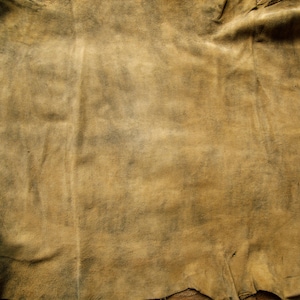Puede incluir: Primer plano de un trozo de cuero marr&oacute;n con textura arrugada. El cuero tiene un aspecto descolorido y desgastado, con algunas manchas m&aacute;s oscuras.