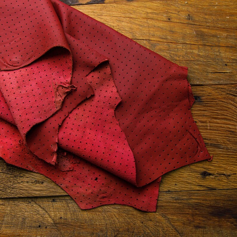 May include: Red leather with a dotted pattern, folded on a wooden surface.