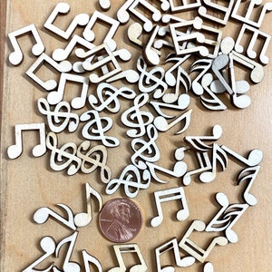 May include: A scattering of wooden music note cutouts in various shapes and sizes, including treble clefs, notes, and eighth notes. A US penny is included for scale.