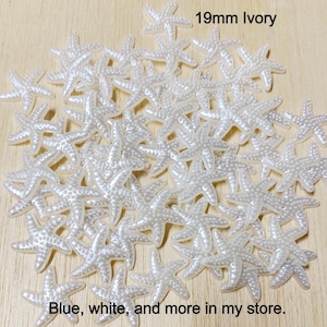 May include: A large pile of 19mm ivory starfish embellishments.  The starfish are made of a pearly white material and have a textured surface.  The text "19mm Ivory" is written in black at the top of the image.