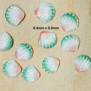 May include: A collection of small, translucent seashell-shaped beads. Each bead is approximately 8.4mm x 8.8mm and features a gradient of colors, transitioning from pink to green. The beads have a textured surface.