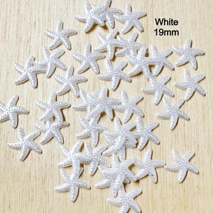 May include: A collection of white starfish embellishments, each measuring 19mm, scattered on a light wood surface. The starfish have a textured surface with small, raised dots. The word "White" is displayed in the image.