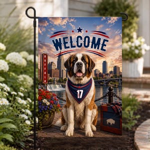 May include: A garden flag featuring a Saint Bernard dog wearing a blue bandana with the number 17, set against a Buffalo city skyline at sunset. The word WELCOME is printed in large blue letters at the top, with a red and blue sign reading BUFFALO.