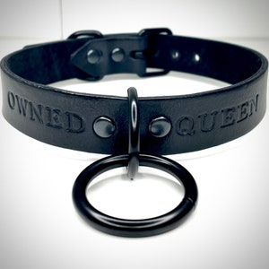 May include: Black leather choker with a metal ring and the words "OWNED QUEEN" embossed on the front.