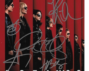Könnte beinhalten: Ein Filmplakat für den Film "Ocean's 8" mit acht Frauen in schwarzer Kleidung vor rotem Hintergrund. Das Plakat ist von den Darstellern signiert.