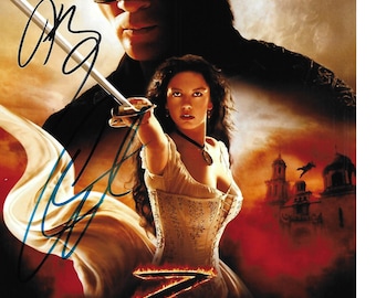 Könnte beinhalten: Ein Filmplakat für "Die Legende von Zorro" mit Antonio Banderas und Catherine Zeta-Jones. Das Plakat hat einen roten, orangen und gelben Hintergrund mit einem großen, stilisierten "Z" in der Mitte. Die Schauspieler sind in Kostümen zu sehen, Banderas als Zorro und Zeta-Jones als Elena. Das Plakat enthält auch den Titel des Films und die Namen der Schauspieler.